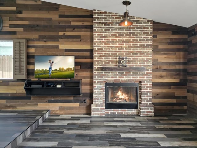 living room featuring dark wood-type flooring, vaulted ceiling, a fireplace, and wooden walls