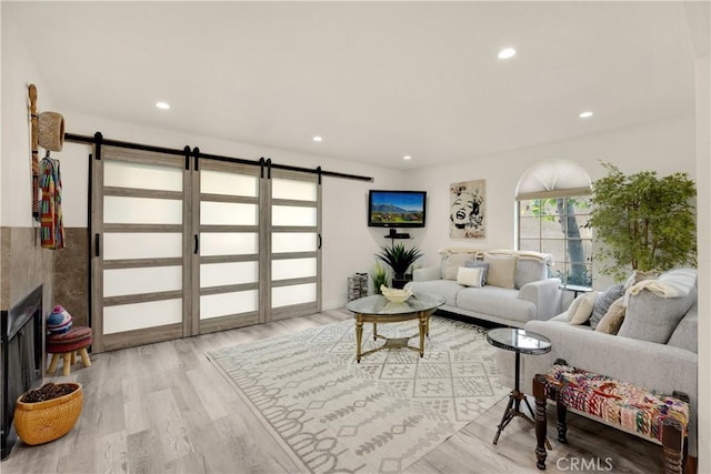 living room featuring light hardwood / wood-style floors, a barn door, and a fireplace