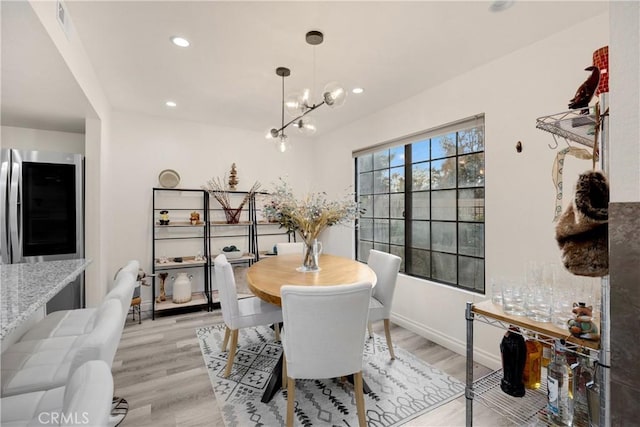 dining space featuring light wood-type flooring and a notable chandelier