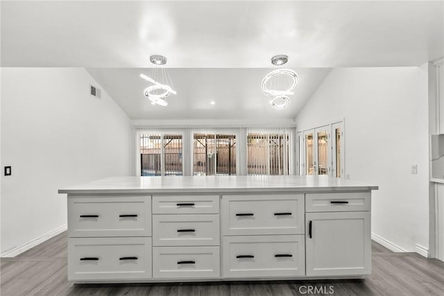 kitchen featuring white cabinets, pendant lighting, dark hardwood / wood-style flooring, and vaulted ceiling