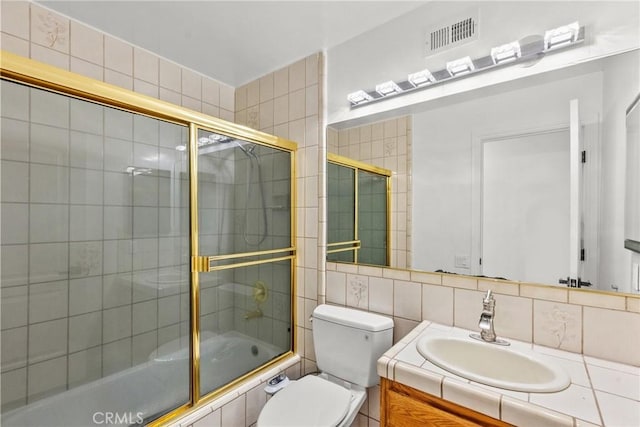 full bathroom with toilet, combined bath / shower with glass door, tile walls, decorative backsplash, and vanity