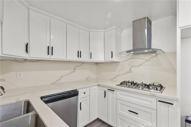 kitchen featuring white cabinets, stainless steel appliances, wall chimney range hood, and light stone counters