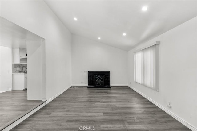 unfurnished living room featuring sink, lofted ceiling, and hardwood / wood-style flooring