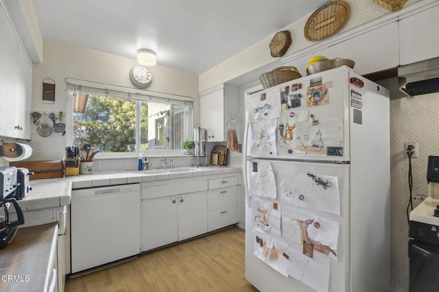 kitchen featuring white appliances, white cabinets, tile counters, decorative backsplash, and sink