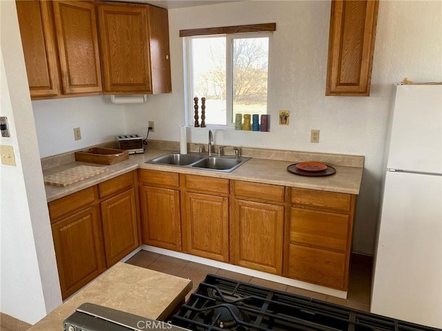 kitchen with white refrigerator, sink, and light tile patterned floors