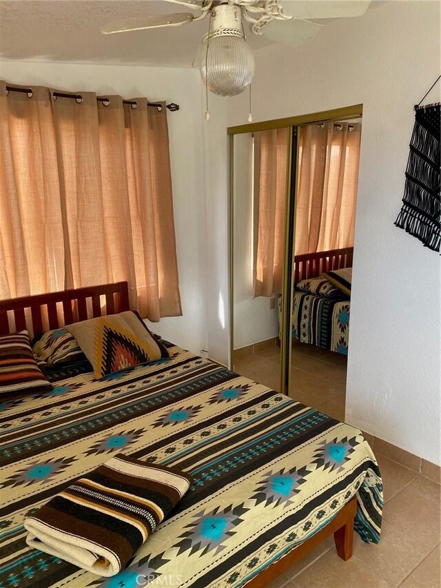 bedroom with ceiling fan, a closet, and light tile patterned floors