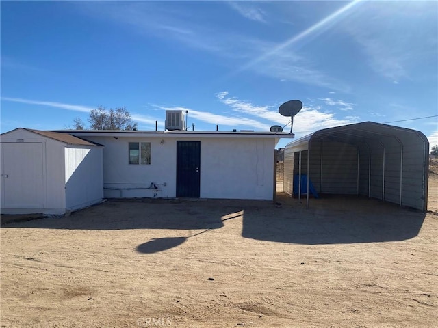 back of house featuring a carport, a shed, and central air condition unit