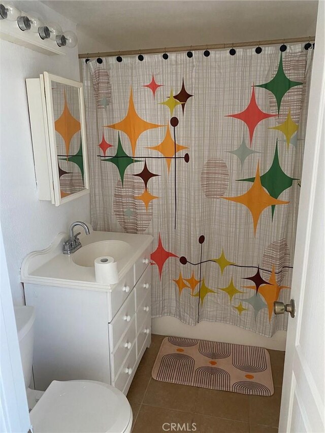 bathroom featuring a shower with shower curtain, vanity, toilet, and tile patterned flooring