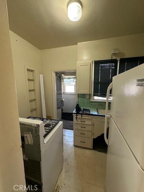 kitchen featuring built in shelves, dark countertops, and white appliances