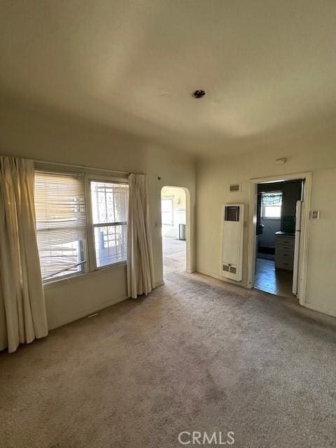 unfurnished living room with arched walkways and carpet