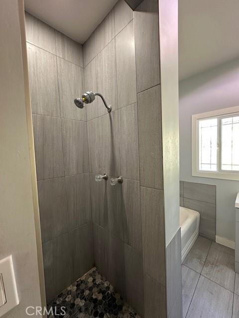 bathroom with a tile shower, vanity, and tile patterned floors