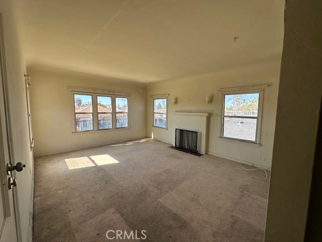 unfurnished living room featuring carpet flooring and a fireplace with flush hearth