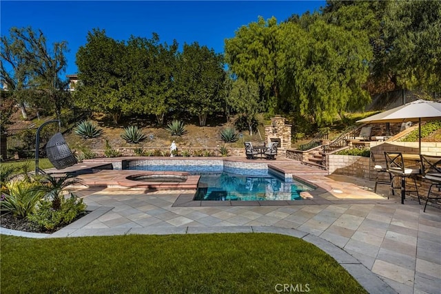 view of pool featuring a patio area, an outdoor stone fireplace, and an in ground hot tub