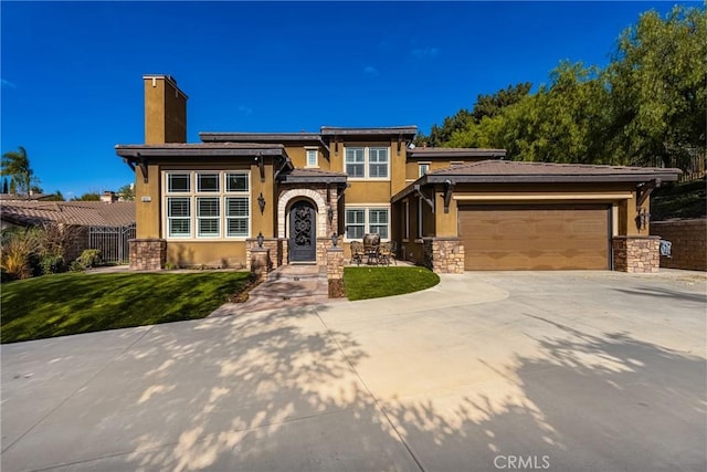 prairie-style home featuring a garage and a front lawn