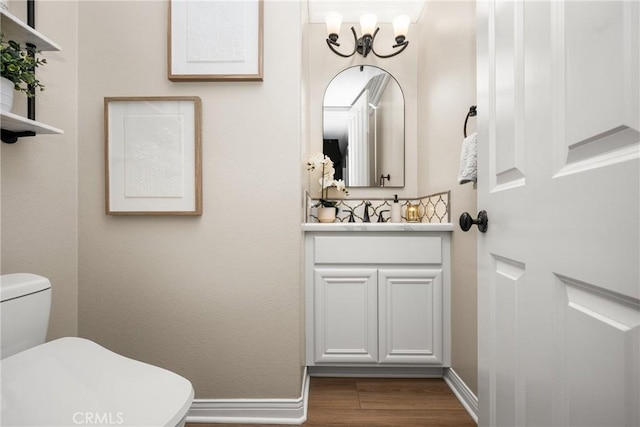 bathroom featuring toilet, vanity, a chandelier, and hardwood / wood-style floors