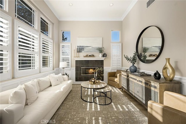 living room featuring a tiled fireplace, dark hardwood / wood-style floors, and ornamental molding