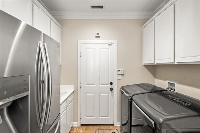 washroom with cabinets, crown molding, washer and clothes dryer, and light hardwood / wood-style floors