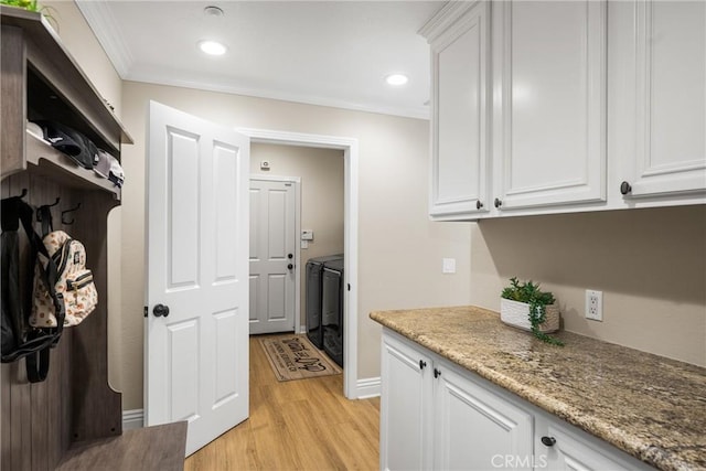 interior space featuring light wood-type flooring, white cabinetry, ornamental molding, and washer and dryer