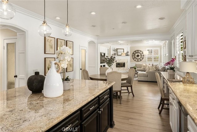 kitchen with light stone countertops, crown molding, and pendant lighting