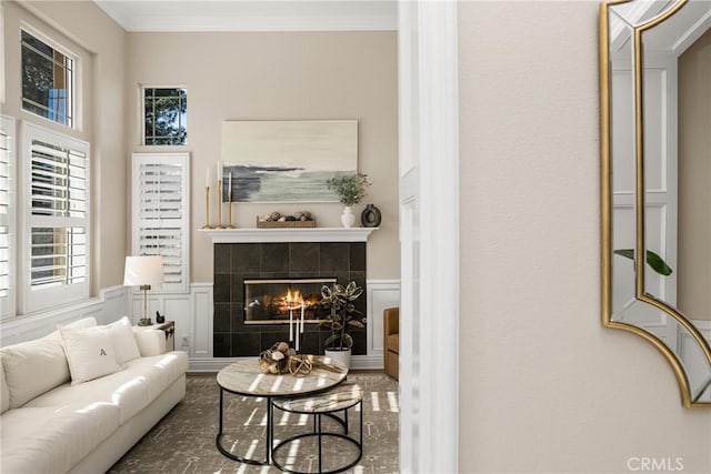 living room featuring a tile fireplace and crown molding