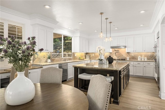 kitchen featuring tasteful backsplash, a kitchen island, pendant lighting, white cabinets, and light stone counters