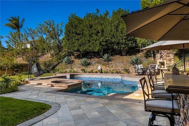 view of swimming pool featuring an in ground hot tub, a patio area, and an outdoor stone fireplace