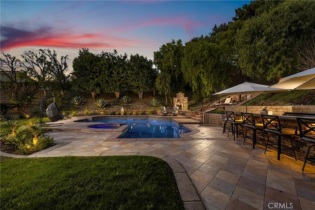 pool at dusk featuring a patio, an in ground hot tub, and an outdoor bar