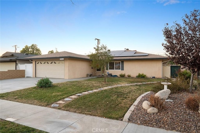 view of front of property with a garage, a front yard, and solar panels