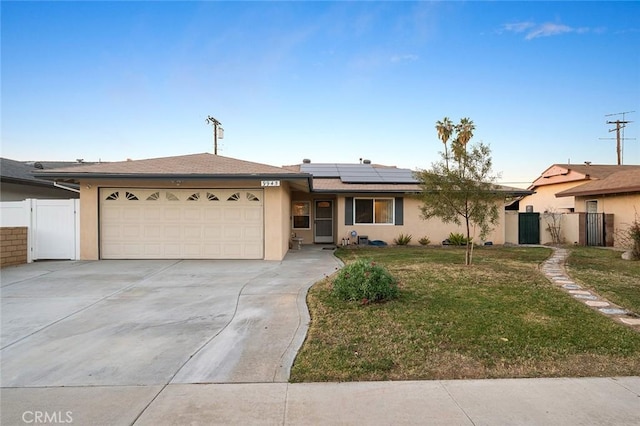 ranch-style house featuring a garage, a front yard, and solar panels