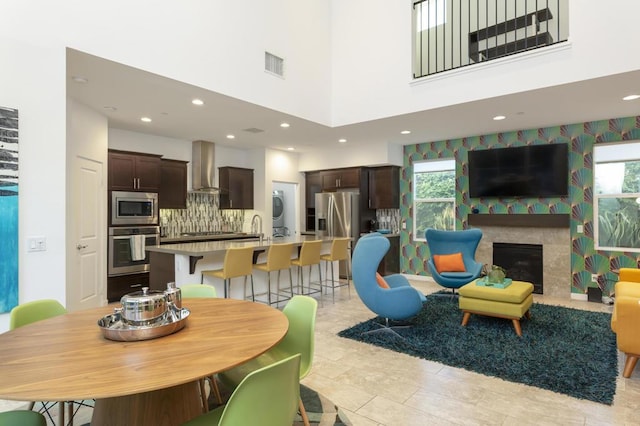 dining room featuring a fireplace, stacked washer / dryer, and a towering ceiling