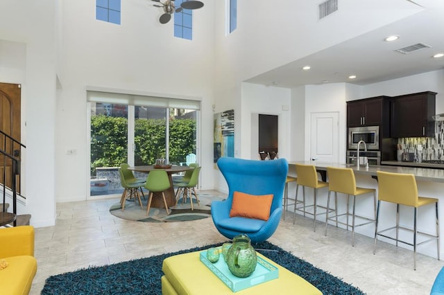 living room featuring ceiling fan and a towering ceiling