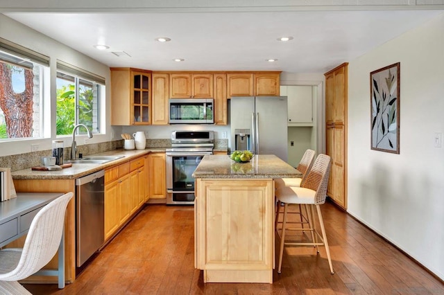 kitchen featuring a kitchen island, a breakfast bar, sink, light wood-type flooring, and appliances with stainless steel finishes