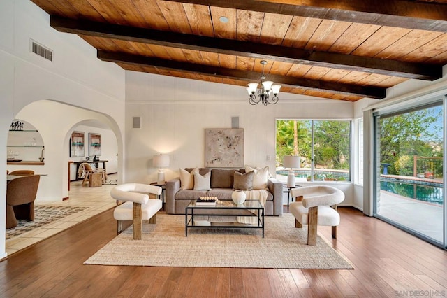 living room featuring hardwood / wood-style floors, lofted ceiling with beams, an inviting chandelier, and wooden ceiling