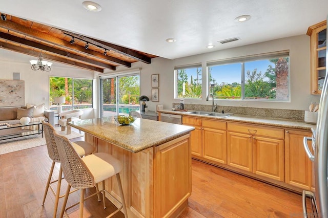 kitchen featuring a center island, an inviting chandelier, sink, light wood-type flooring, and stainless steel dishwasher