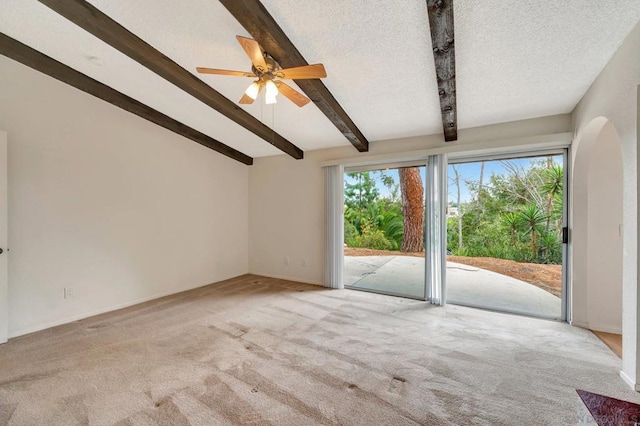 carpeted spare room with a textured ceiling, ceiling fan, and vaulted ceiling with beams