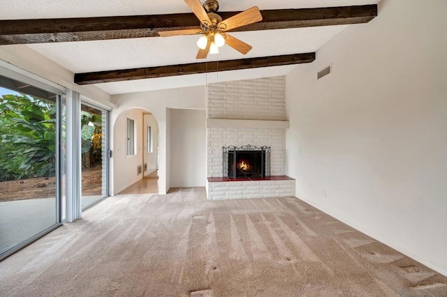 unfurnished living room with ceiling fan, light carpet, lofted ceiling with beams, and a fireplace