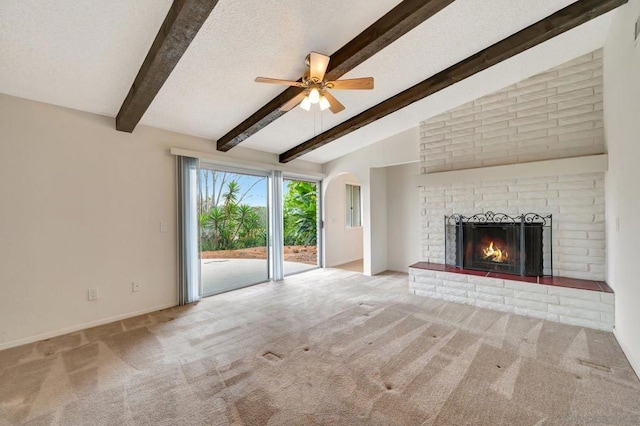 unfurnished living room featuring ceiling fan, a brick fireplace, lofted ceiling with beams, a textured ceiling, and light carpet