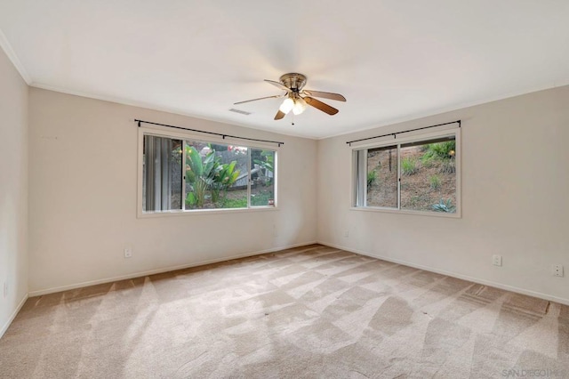 unfurnished room with ceiling fan, light colored carpet, plenty of natural light, and ornamental molding