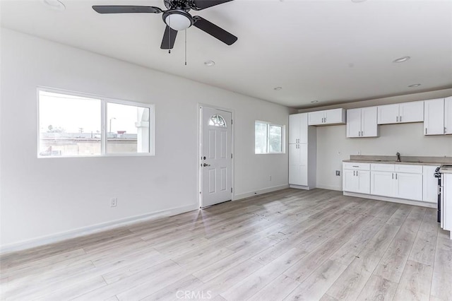 interior space with a sink, light wood-style flooring, a ceiling fan, and white cabinets