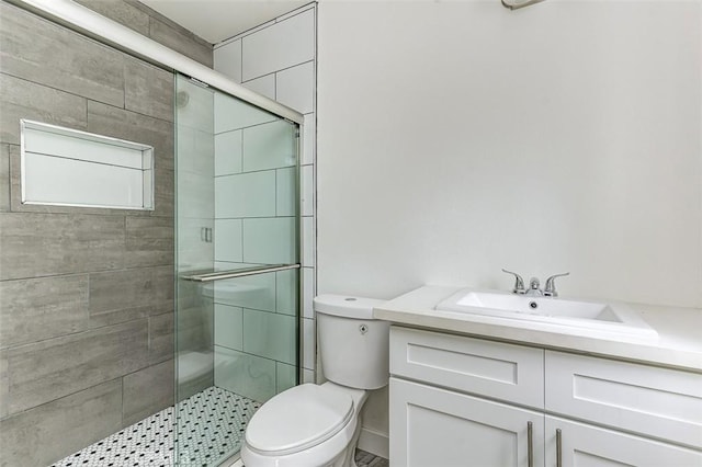 bathroom featuring vanity, a shower stall, and toilet