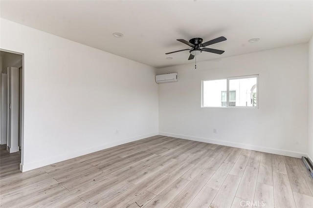 spare room with baseboards, light wood finished floors, a ceiling fan, and a wall mounted AC