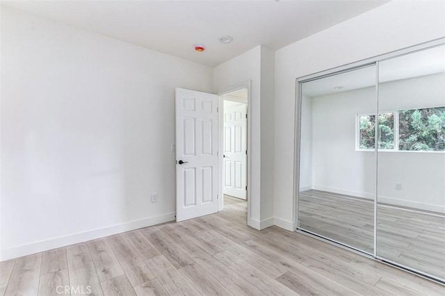 unfurnished bedroom featuring a closet, baseboards, and wood finished floors