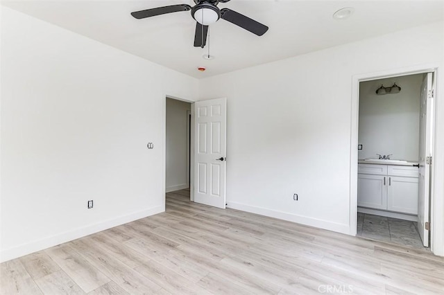 unfurnished bedroom featuring a ceiling fan, baseboards, a sink, light wood-type flooring, and connected bathroom