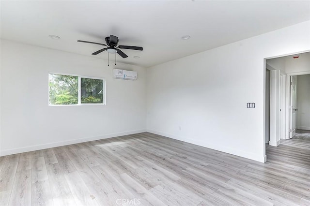 empty room with a wall unit AC, light wood-style flooring, a ceiling fan, and baseboards