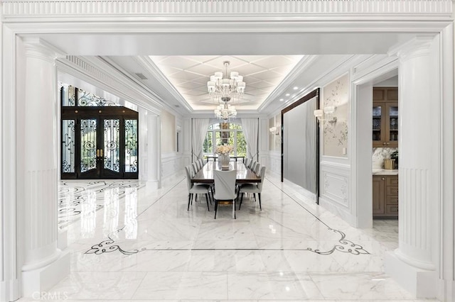 dining area featuring french doors, an inviting chandelier, ornamental molding, a raised ceiling, and decorative columns