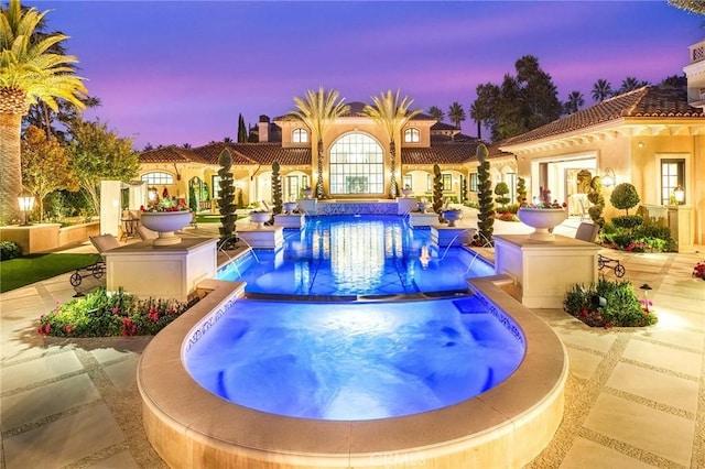 pool at dusk featuring pool water feature