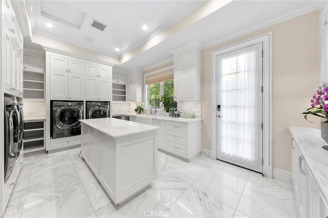 clothes washing area with independent washer and dryer, ornamental molding, and cabinets