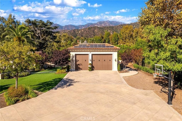 exterior space featuring a mountain view, a lawn, solar panels, and a garage