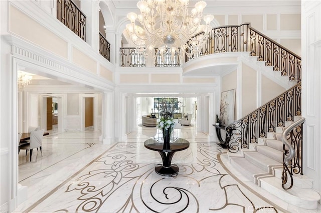 foyer with a towering ceiling, a chandelier, and ornamental molding