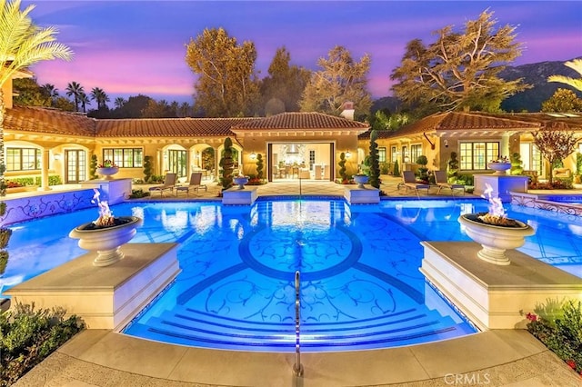 pool at dusk with french doors and a patio